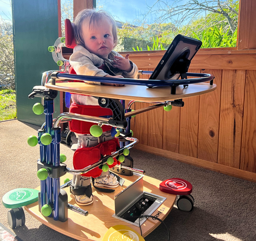 Alba is a toddler in a supportive stander with iPad